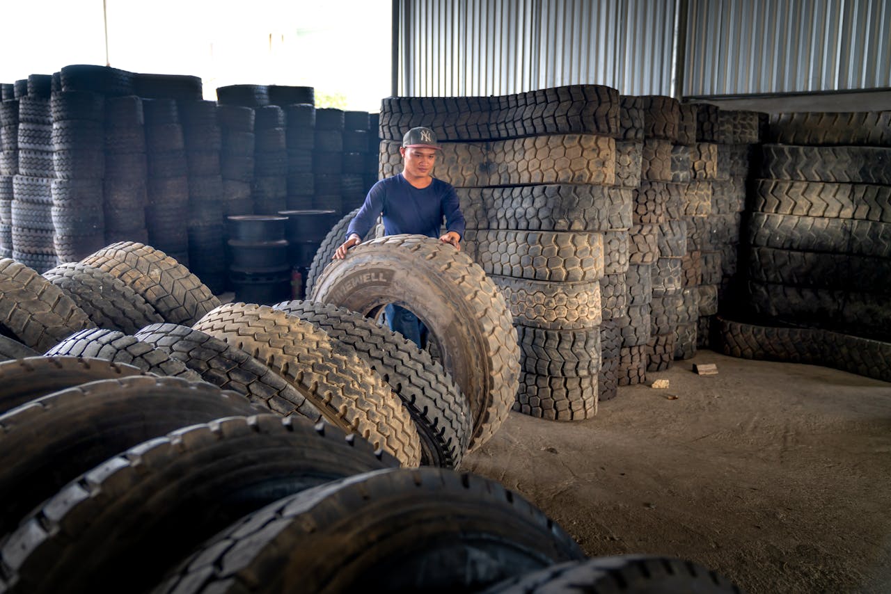 hero-img-02 Man organizing large industrial tires in a warehouse, showcasing labor and storage setup.