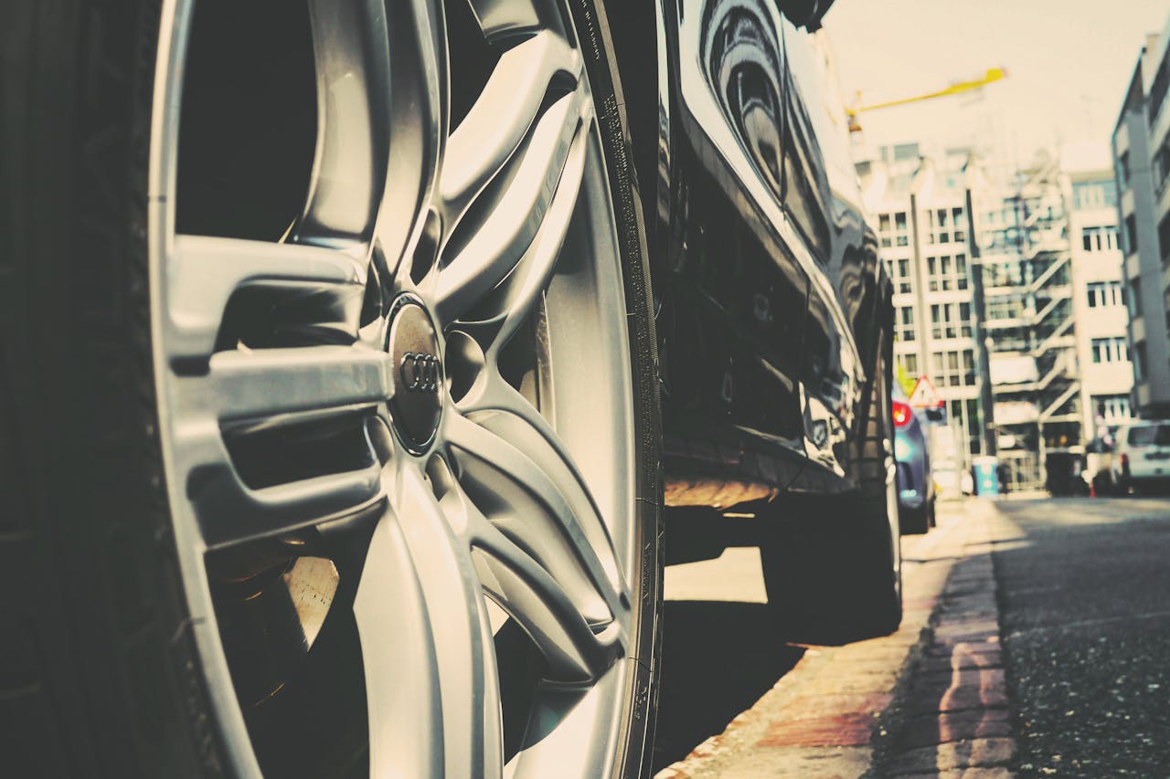 our-services-3 Detail of a car wheel on a city street with buildings in the background. Urban vibe.