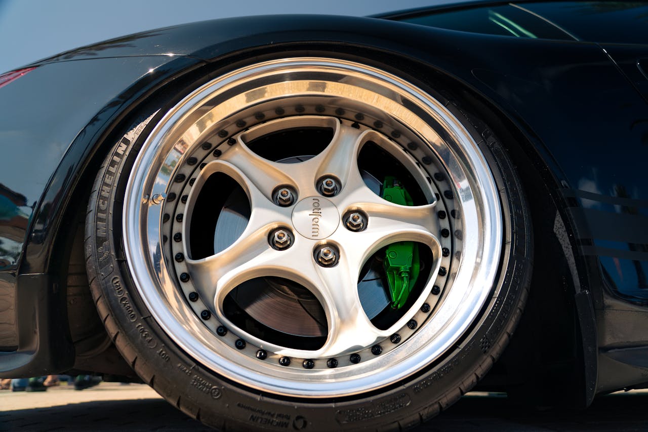 about-01 Detailed shot of a custom car wheel with chrome rim and green brake caliper.