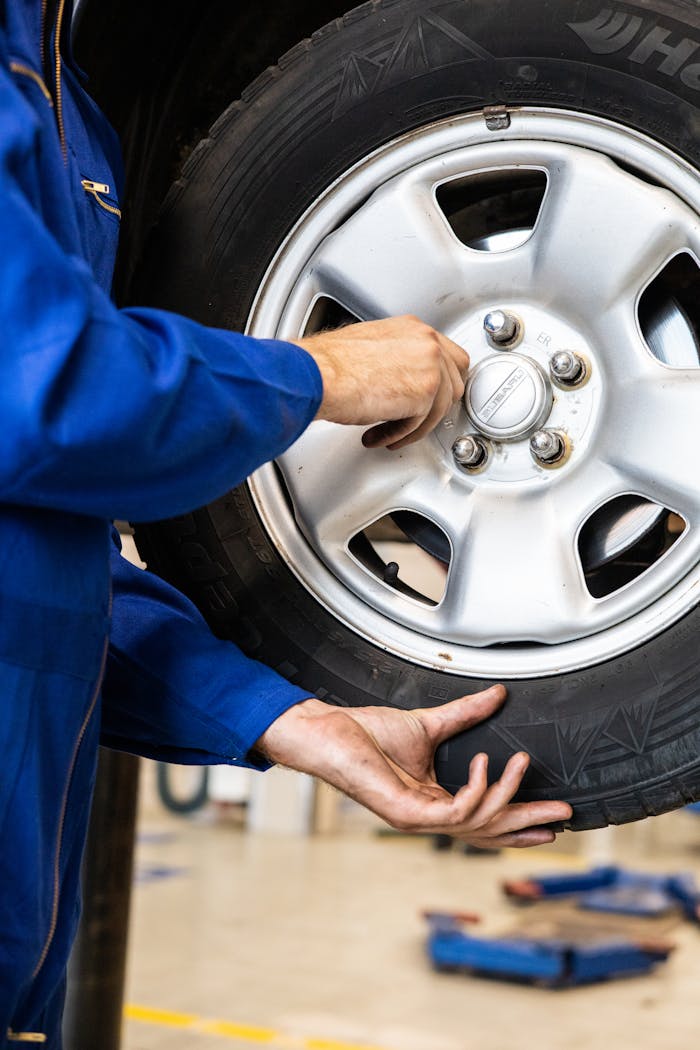 our-services-2 A mechanic tightens bolts on a car wheel in a professional garage setting.